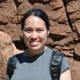 Woman with black hair pulled back in front of a rock formation